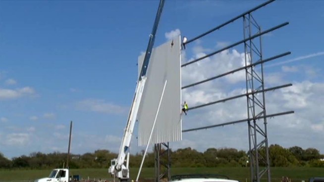 Crews are installing the three screens at a drive-in under construction in the Trinity Uptown development just north of downtown Fort Worth.