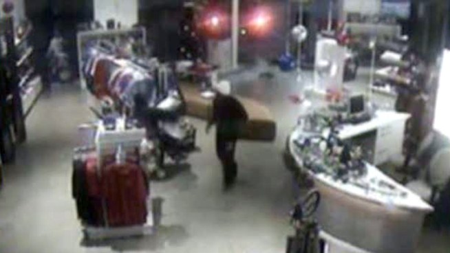 Surveillance video shows two people drive a pickup truck into a Texas Rangers store in Dallas and steal Rangers paraphernalia.