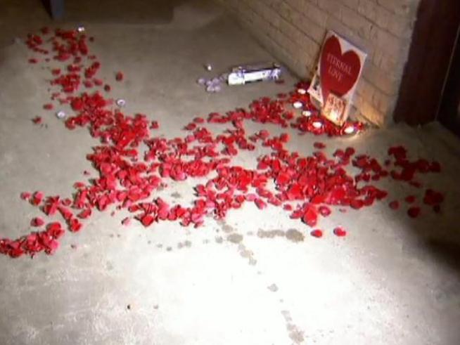 The slain officer's widow and other loved ones scatter rose petals at the site of his death.