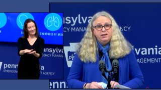 A woman at a podium with a sign language interpreter