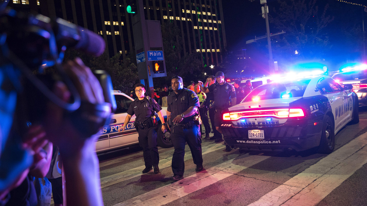 Bystanders stand near police barricades following a deadly shooting in downtown Dallas on Thursday, July 7, 2016. Five officers were killed when gunfire erupted at the end of a protest.