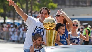 Dallas Mavericks owner Mark Cuban rides with the NBA Championship basketball trophy and his family wife Tiffany, holding son Jake, and daughters Alexis Sofia, right, and Alyssa, during the team's victory parade in downtown Dallas, Thursday, June 16, 2011.