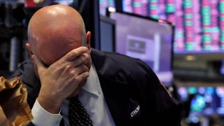 In this March 12, 2020, file photo, a trader has his head in his hand on the floor of the New York Stock Exchange.