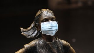 In this file photo, a surgical mask is placed on The "Fearless Girl" statue outside the New York Stock Exchange on Thursday, March 19, 2020, in New York.