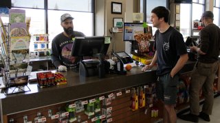 Mike Johnston, a clerk at the Maupin Market in tiny Maupin, Oregon, helps a customer while wearing latex gloves