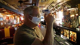 Cheers to You bar owner Bob Brown tests a thermometer at his bar Friday, May 1, 2020, in Salt Lake City.