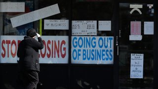 A woman looks at signs at a store in Niles, Ill., Wednesday, May 13, 2020.
