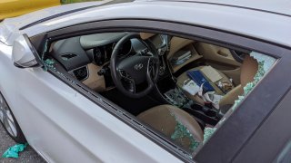 a parked car with a broken driver's side window after a smash-and-grab break-in