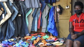 Grace Twisimire, 25, sits in her once-thriving shop selling clothes and plastic shoes in the capital Kampala, Uganda