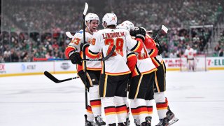 Elias Lindholm #28, Sean Monahan #23 and the Calgary Flames celebrate a goal against the Dallas Stars at the American Airlines Center on Dec. 22, 2019 in Dallas, Texas.