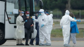 Passengers from the Grand Princess, a cruise ship carrying multiple people who have tested positive for COVID-19, exit a bus before boarding a chartered plane in Oakland, Calif., Tuesday, March 10, 2020. The passengers on the flight are going to San Antonio to be quarantined at Lackland Air Force Base.