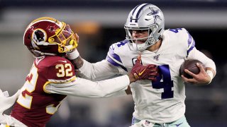 Dak Prescott #4 of the Dallas Cowboys fends off a tackle attempt by Jimmy Moreland #32 of the Washington Redskins in the third quarter in the game at AT&T Stadium on December 29, 2019 in Arlington, Texas.
