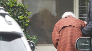 Charlie Campbell a retired RN from Silver City, New Mexico, takes his mom Dorothy Campbell, 88, of Bothell to see her husband Gene Campbell, 89, through his room window on March 5, 2020 at the Life Care Center nursing home in Kirkland, Washington where multiple cases of COVID-19 have been linked and some patients have died.