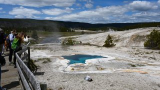 Tourists take pictures at the Blue Star spring near Old Faithful Upper Geyser Basin in Yellowstone National Park in Wyoming on June 11, 2019. Old Faithful has erupted every 44 to 125 minutes since 2000.
