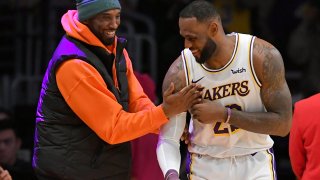 LeBron James #23 of the Los Angeles Lakers has a moment on the sideline with former Laker Kobe Bryant in the second half during a game against the Dallas Mavericks at Staples Center on December 29, 2019 in Los Angeles, California.