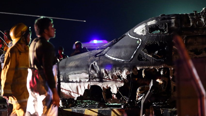 Rescuers stand next to the wreckage of a Westwind aircraft after it caught on fire during takeoff at Manila international airport in Manila