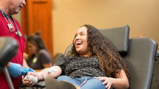 woman donating blood with red cross