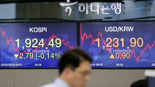 In this May 18, 2020, file photo, a currency trader walks near the screens showing the Korea Composite Stock Price Index (KOSPI), left, and the foreign exchange rate between U.S. dollar and South Korean won at the foreign exchange dealing room in Seoul, South Korea.