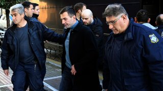 Greek police officers escort two of the seven suspects, center, allegedly involved in the fatal beating of Texan tourist Bakari Henderson as they disembark a police bus at a court house in Patras city, western Greece, Jan. 8, 2020. A Greek court has postponed the retrial of seven suspects on murder charges over the 2017 fatal beating of a Texan tourist on an island resort.
