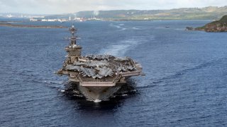 In this June 4, 2020, photo provided by the U.S. Navy, the aircraft carrier USS Theodore Roosevelt (CVN 71) departs Apra Harbor in Guam. The carrier has returned to sea and is conducting military operations in the Pacific region 10 weeks after a massive coronavirus outbreak sidelined the Navy warship.