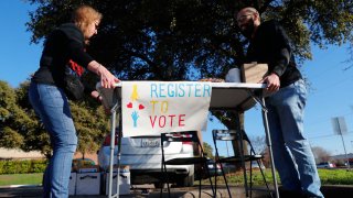 Democratic Party voting drive volunteers move a table after the manager of the nearby coffee shop asked them to leave the front store’s parking lot in Richardson, Texas, Saturday, Jan. 18, 2020. Democrats are hoping this is the year they can finally make political headway in Texas and have set their sights on trying to win a majority in one house of the state Legislature. Among the hurdles they’ll have to overcome are a series of voting restrictions Texas Republicans have implemented in recent years, including the nation’s toughest voter ID law, purging of voter rolls and reductions in polling places.