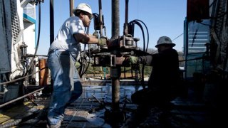 FILE: Toronto-based Trinidad Drilling Ltd. floorhands Julio Serrato, left, and Jaime Gonzalez work on the first drilling of the Reveille 1H Chesapeake Energy Corp. natural gas rig in Fort Worth, Texas, U.S., on Monday, Nov. 23, 2009. Chesapeake Energy, a shale drilling pioneer that helped to turn the United States into a global energy powerhouse, said it would file for bankruptcy protection Sunday, June 28, 2020.