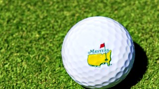 A golf ball with The Masters logo on the grass