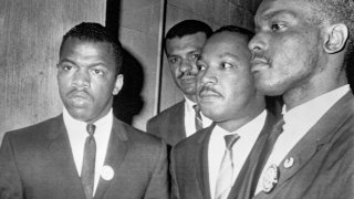 Reverend Martin Luther King Jr., (center) is escorted into a mass meeting at Fish University in Nashville. His colleagues are, left to right, John Lewis, national chairman of the Student Non-Violent Committee and Lester McKinnie, on of the leaders in the racial demonstrations in Nashville recently. King gave the main address to a packed crowd.