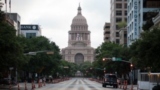 Cars drive on Congress Avenue in front of the Texas Capitol building