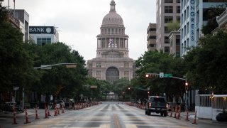 Cars drive on Congress Avenue in front of the Texas Capitol building