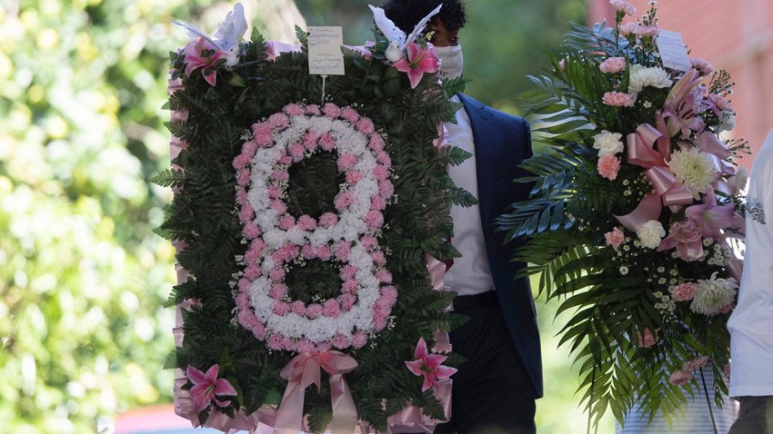 A man carries flowers into a viewing for 8-year-old Secoriea Turner, who was fatally shot in Atlanta on July 4th near the Wendy's site where Rayshard Brooks was killed the previous month, July 14, 2020, in South Fulton, Ga.