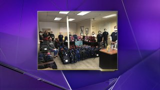 people in masks donating backpacks