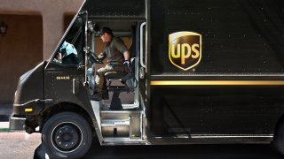 A UPS driver sits in a UPS big brown truck