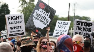 Counter protesters wave signs during a far-right rally on Aug. 15, 2020, near the downtown of Stone Mountain, Georgia. Georgia’s Stone Mountain Park, which is famous for its large rock carving of Confederate leaders, planned to close on Saturday in response to a planned right-wing rally.