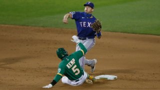 Nick Solak #15 of the Texas Rangers gets out Tony Kemp #5 of the Oakland Athletics at second base and turns a double play in the bottom of the eighth inning at Oakland-Alameda County Coliseum on August 04, 2020 in Oakland, California.