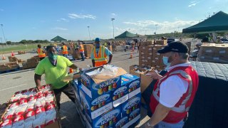 Men stand outside next to palets of food to be donated.