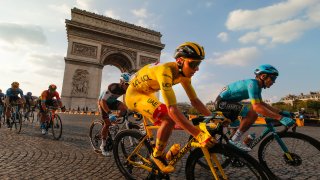 Slovenia's Tadej Pogacar, wearing the overall leader's yellow jersey, rides past the Arc de Triomphe on the Champs-Elysees