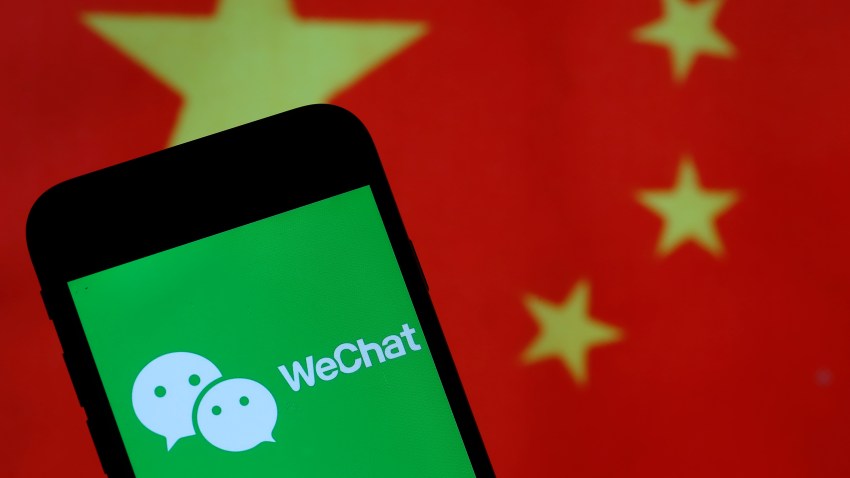 The WeChat logo is displayed on the screen of a smartphone in front of a Chinese flag