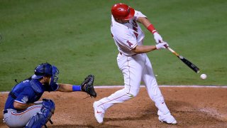 Mike Trout #27 of the Los Angeles Angels hits an RBI single in front of Jeff Mathis #2 of the Texas Rangers, to take a 4-3 lead, during the eighth inning at Angel Stadium of Anaheim on Sept. 19, 2020 in Anaheim, California.