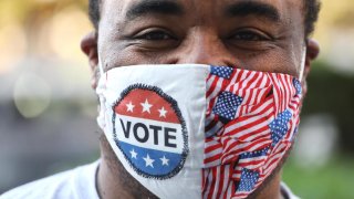 A voter smiles behind a mask.