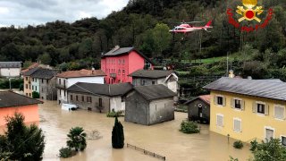 a firefighters' helicopter flies over flooding in the town of Ornavasso, in the northern Italian region of Piedmont