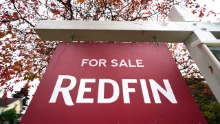 A Redfin "for sale" sign stands in front of a house