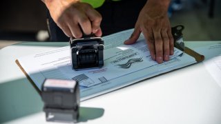 A worker stamps a ballot at a drive-thru mail ballot hand delivery center in Austin, Texas, U.S., on Friday, Oct. 2, 2020. Governor Abbott announced that every county in Texas would only be allowed one drop off box for mail in ballots, citing concerns of voter fraud.