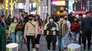 People with and without masks walk in Times Square