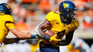 Running back Leddie Brown #4 of the West Virginia Mountaineers takes a hand-off from quarterback Jarret Doege #2 against the Oklahoma State Cowboys in the first quarter on Sept. 26, 2020 at Boone Pickens Stadium in Stillwater, Oklahoma. OSU won 27-13.