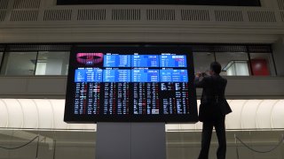 A man takes a photograph of a stock board inside the Tokyo Stock Exchange (TSE), operated by Japan Exchange Group Inc. (JPX), in Tokyo, Japan, on Monday, March 11, 2019.