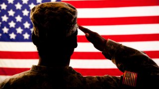 A military veteran salutes the American flag.