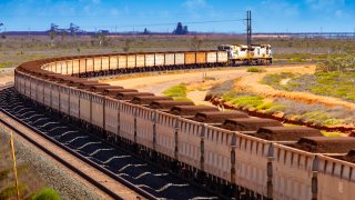 A freight train carrying iron ore travels along a rail track towards Port Hedland, Australia, on Monday, March 18, 2019.