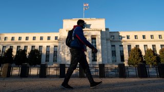 A man wearing a face mask walks past the U.S. Federal Reserve in Washington, D.C., the United States, on Dec. 2, 2020.