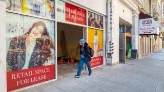 A person wearing a protective mask walks past a store for lease in San Francisco, Calif., on Dec. 8, 2020.
